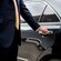 A professional driver in a suit opening the rear door of a luxury sedan